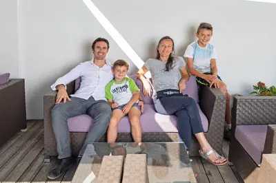 a family sitting on a couch in a living room at Hotel Gardenazza in Badia