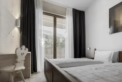 a bedroom with a bed and a window and a chair at Hotel Gardenazza in Badia