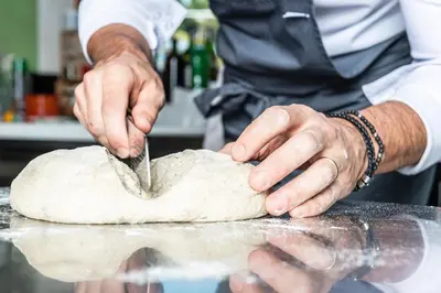a man is making a dough with a knife at Hotel Gardenazza in Badia