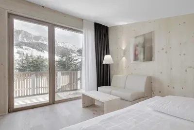a bedroom with a bed and a couch and a window at Hotel Gardenazza in Badia