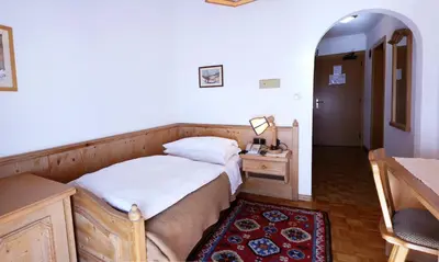 a bedroom with a bed and a table with a lamp at Hotel Dolomiti Madonna in Ortisei