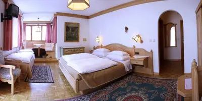 a bedroom with two beds and a desk in it at Hotel Dolomiti Madonna in Ortisei