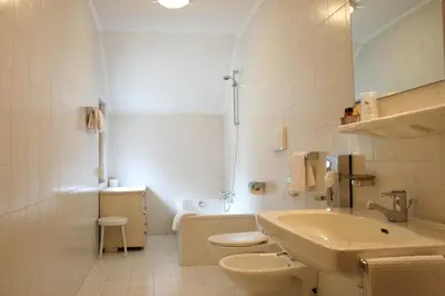 a white bathroom with a sink and a toilet at Hotel Dolomiti Madonna in Ortisei