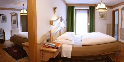 a bedroom with two beds and a window at Hotel Dolomiti Madonna in Ortisei