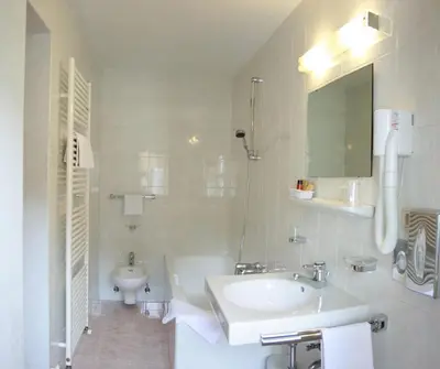 a white bathroom with a sink and a toilet at Hotel Dolomiti Madonna in Ortisei