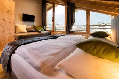 two beds in a room with a large window at hubertus dolomites in Fiè