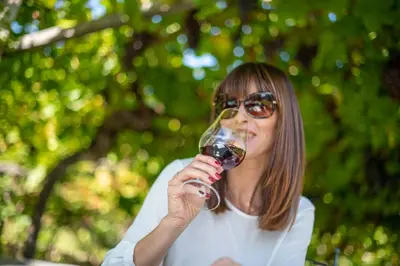 a woman drinking a glass of red wine at Gartenheim Tramin in Termeno