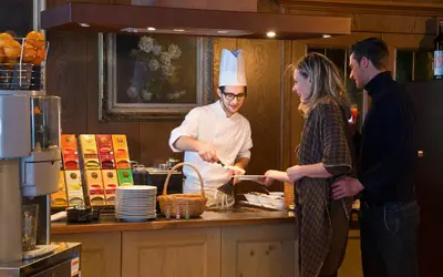 a man and a woman in a kitchen preparing food at Alpin & Vital Hotel La Perla in Ortisei