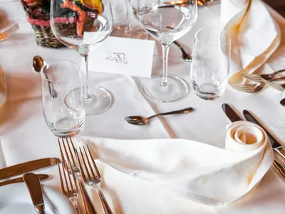 a white table with silverware and wine glasses at Alpin & Vital Hotel La Perla in Ortisei