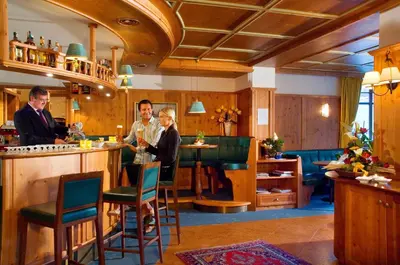 a group of people standing at a bar at Alpin & Vital Hotel La Perla in Ortisei