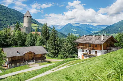 a building on a hill with a castle in the background at Sprechenstein in Vipiteno