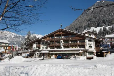 a large building in the snow in front of a mountain at Sport Hotel Majarè in Pozza di Fassa