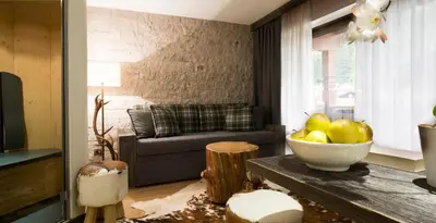 a living room with a couch and a bowl of fruit on a table at Sport Hotel Majarè in Pozza di Fassa