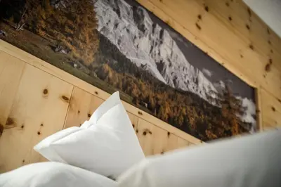 a pillow on a bed with a painting on the wall at Gourmet Hotel Gran Ander in Badia