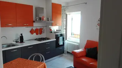 a kitchen with blue cabinets and a red chair in it at Casa Novella in Revò