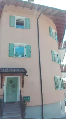 a building with green windows and a door at Casa Novella in Revò