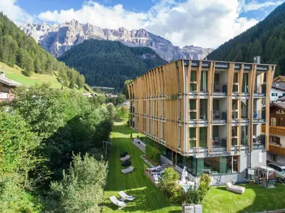 a building with people standing outside of it in the snow at Mountain Design Hotel Eden Selva in Selva di Val Gardena