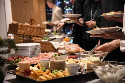 a buffet of food with people holding plates of food at Mountain Design Hotel Eden Selva in Selva di Val Gardena