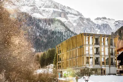 a building in front of a snow covered mountain at Mountain Design Hotel Eden Selva in Selva di Val Gardena