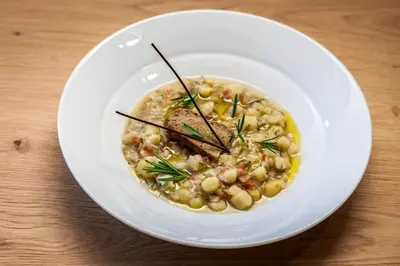 a white plate with a bowl of food on a table at Mountain Design Hotel Eden Selva in Selva di Val Gardena
