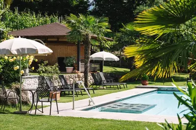 a pool with chairs and umbrellas in a yard at Alagundis Apartment Residence in Lagundo