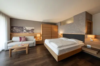a bedroom with a large bed and a couch at Alagundis Apartment Residence in Lagundo