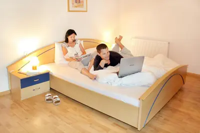 a man and a woman sitting on a bed with a laptop at Residence St Konstantin in Fiè