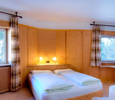 a bedroom with a bed with two lamps on it at Sporthotel Spoegler in Collalbo