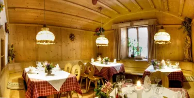 a dining room with tables and chairs and chandeliers at Sporthotel Spoegler in Collalbo