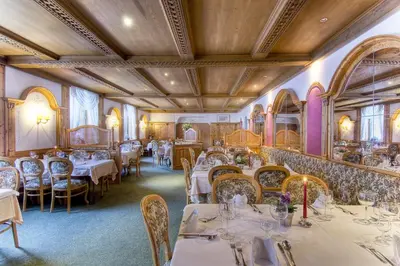 a restaurant with tables and chairs in a room at Sporthotel Spoegler in Collalbo