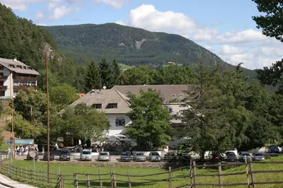 a house with cars parked in a parking lot with a mountain at Sporthotel Spoegler in Collalbo