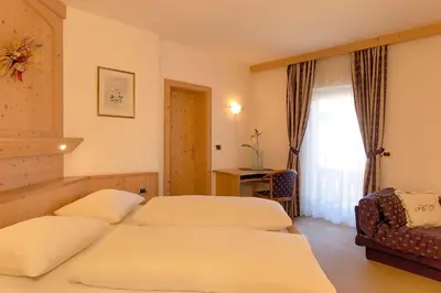 a hotel room with two beds and a window at Hotel Teresa in San Vigilio Di Marebbe