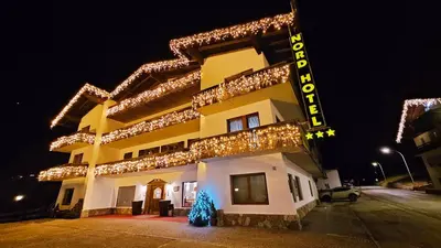 a building with flowers on the balconies of it at Nord Hotel in Cortina dʼAmpezzo