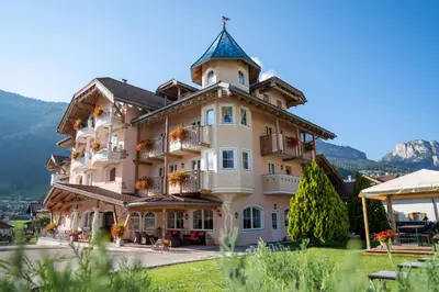 a dining room with a table and chairs and a tv at Hotel Chalet Sas Morin in Pozza di Fassa