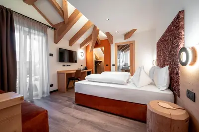 a hotel room with a large bed and a desk at Hotel Chalet Sas Morin in Pozza di Fassa