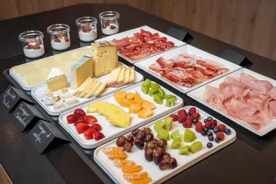 a table topped with different types of cheese and fruit at Hotel Chalet Sas Morin in Pozza di Fassa