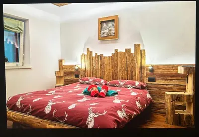 a bedroom with a wooden bed with red sheets and red pillows at Cèsa Mia in Campitello di Fassa