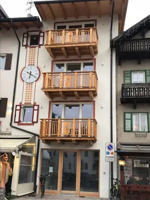 a building with wooden balconies and a clock on it at Cèsa Mia in Campitello di Fassa