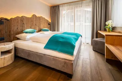 a bedroom with a large bed with a wooden headboard at Garni Mia Co in Antermoia