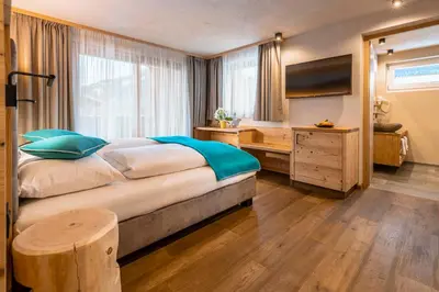 a bedroom with a large bed with a desk and a television at Garni Mia Co in Antermoia