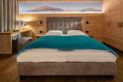 a bedroom with a large bed with a painting on the wall at Garni Mia Co in Antermoia