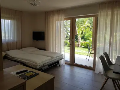 a bedroom with a bed and a sliding glass door at Gartenappartements Die Mühle - ADULTS ONLY in Caldaro