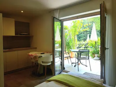 a bedroom with a door open to a patio with a table and chairs at Gartenappartements Die Mühle - ADULTS ONLY in Caldaro