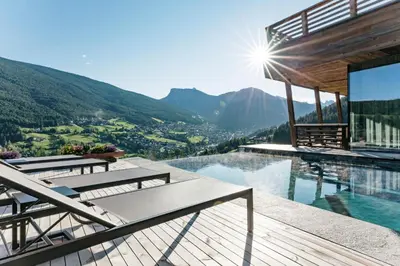a house on a mountain with a swimming pool at Hotel Niblea Dolomites in Ortisei
