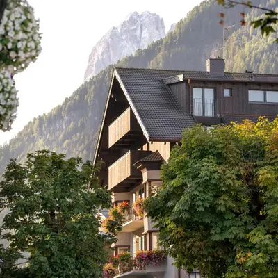 a large building with trees in front of a mountain at Hotel Garni Planaces in Ortisei
