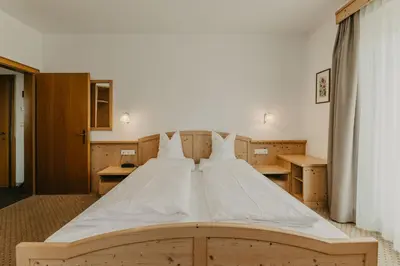 a large white bed in a room with wooden cabinets at Hotel Garni Planaces in Ortisei