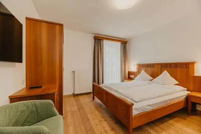 a bedroom with a bed and a chair at Hotel Garni Planaces in Ortisei