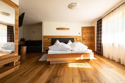 a bedroom with a bed with a wooden headboard at Garni Hotel Geier in Santa Cristina in Val Gardena