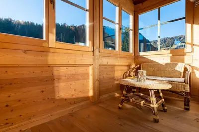 a room with a table and a chair and windows at Garni Hotel Geier in Santa Cristina in Val Gardena