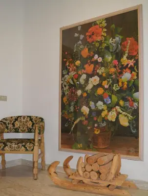 a painting of flowers in a vase next to a chair at Hotel Stella Alpina in Bellamonte
